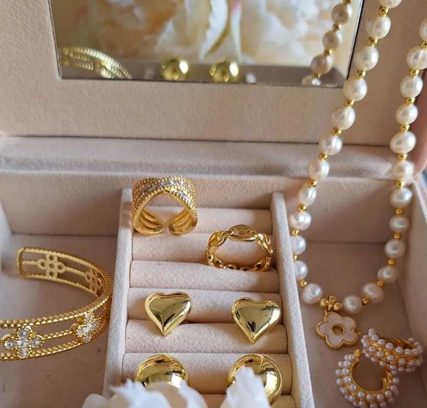An ornate box containing an array of gold jewelry pieces and shimmering pearls, highlighting luxury and elegance.