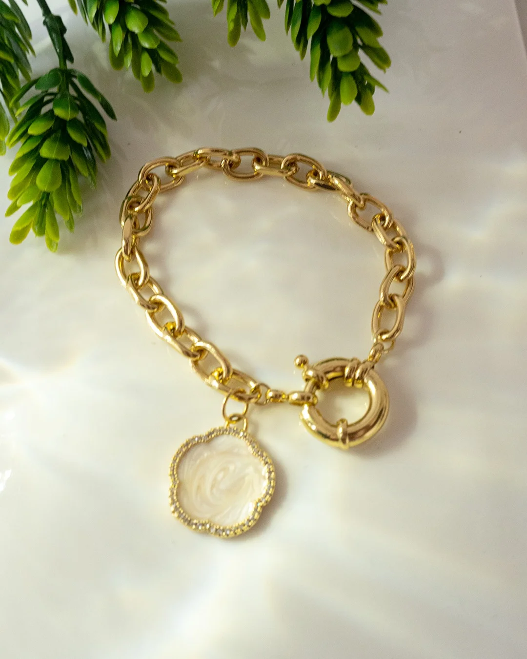 A gold bracelet featuring a coin charm and a delicate flower design, showcasing elegance and intricate craftsmanship.